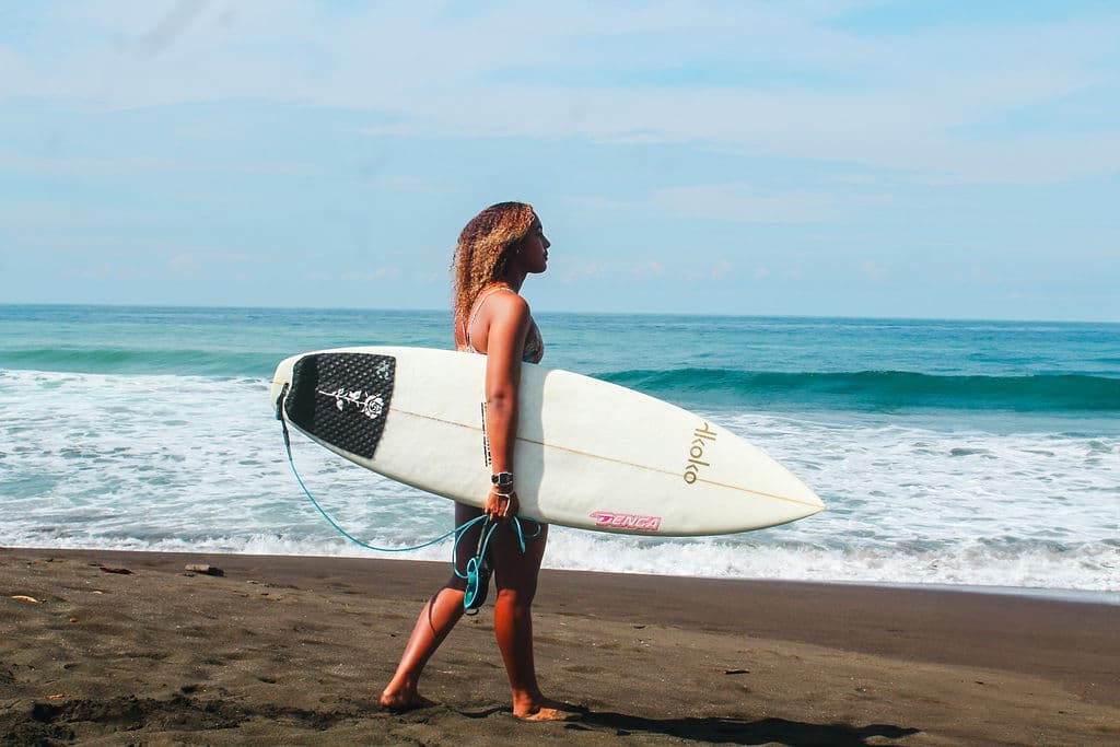 Surfer on the black sand of Playa Hermosa