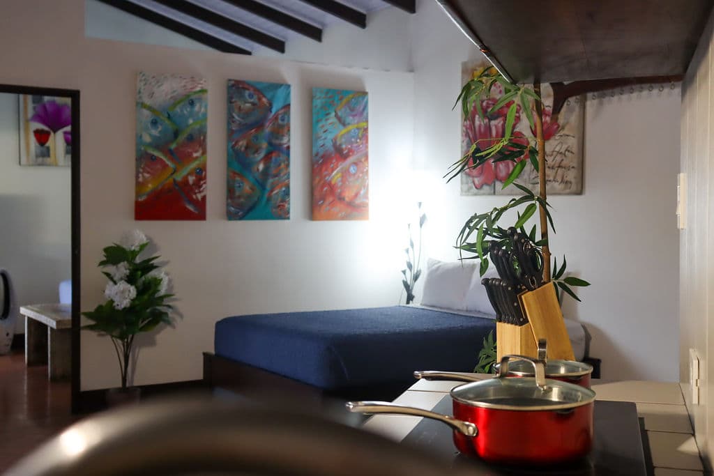 Villa great room with a bed, fish-art triptych and a kitchen counter with cookware and knives