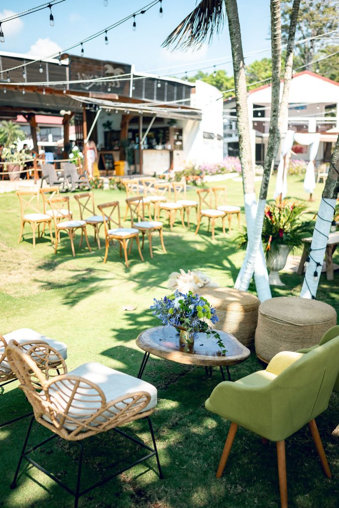Zona lounge del jardín con mobiliario de mimbre y flores