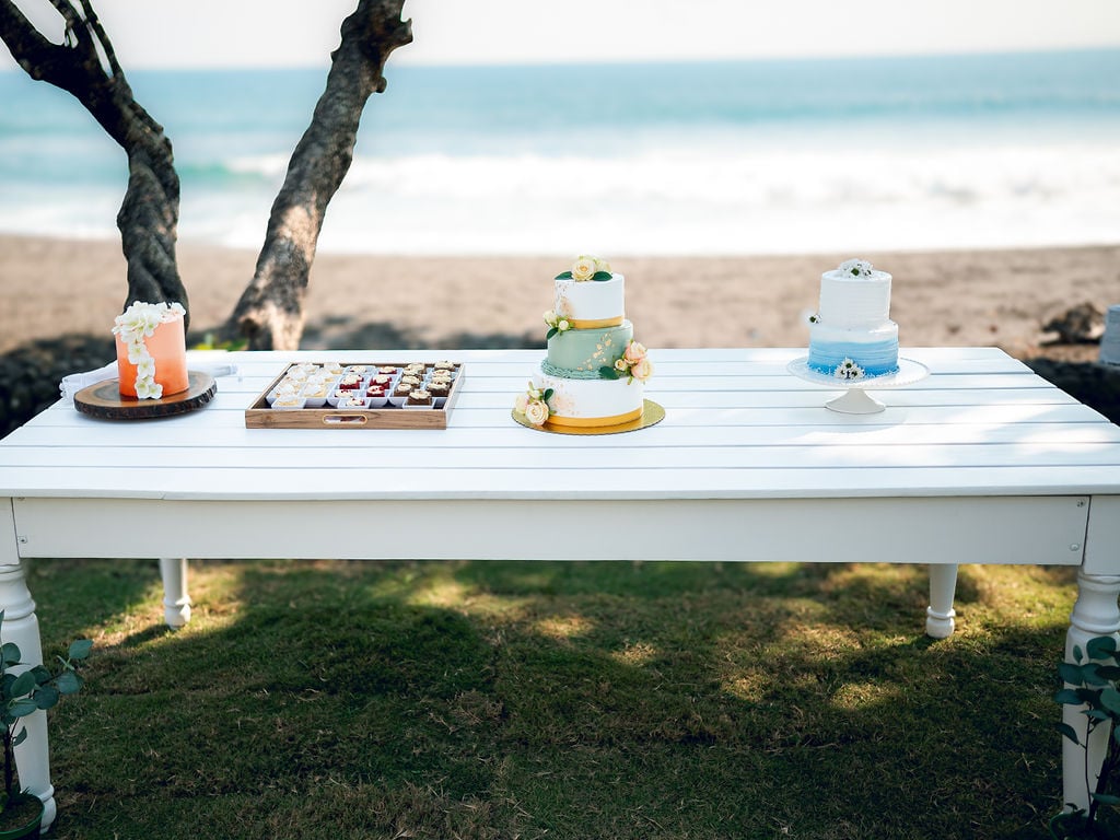 Mesa de postres y pasteles de boda montada frente a la playa