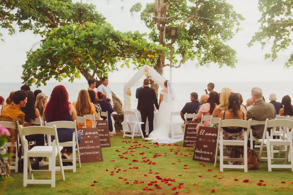 Los novios en el pasillo de pétalos, rodeados de sus invitados